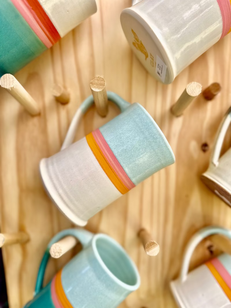 Colorful mugs hanging on a wooden pegboard